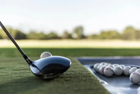 A golf club ready to hit a golf ball on a driving range.