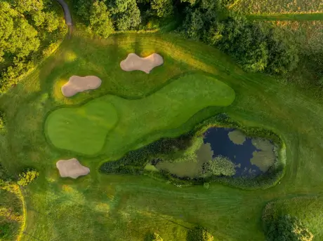 Aerial view of a golf course with fairways, sand traps, and a pond.