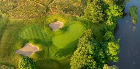 Aerial view of a stunning golf course with greens, bunkers, and trees.