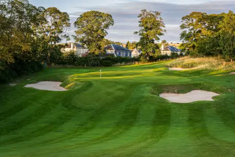 Scenic view of a golf course with sand bunkers and trees in the background.