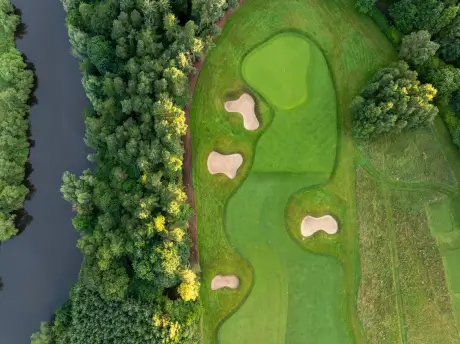 Aerial view of a picturesque golf course with sand traps and trees.