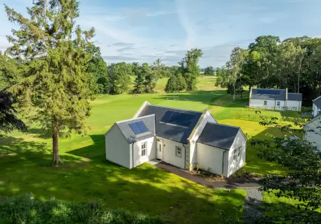 Modern house on a golf course surrounded by a lush green landscape.