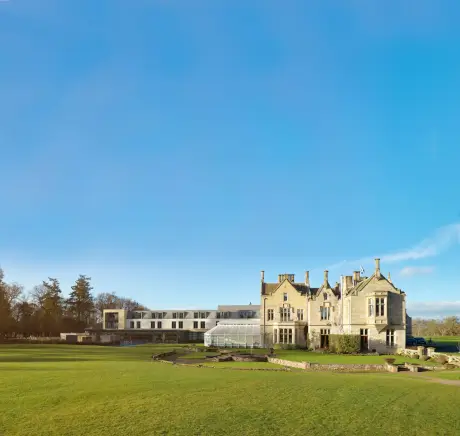 Elegant estate blending modern and traditional styles with lush green lawn under a clear blue sky.