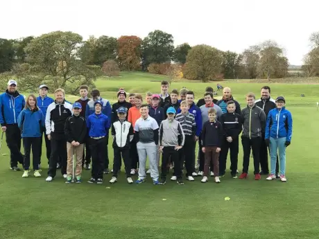 Young golfers gathering at the golf course for a group photo.